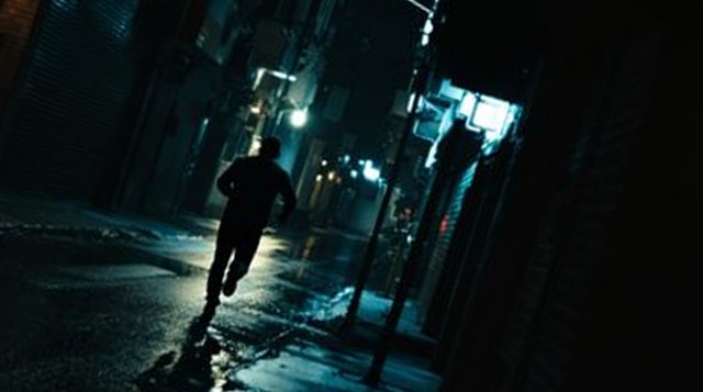 Dutch Angle example: a tilted frame of a man running down a wet alley at night, horizon at 20 degrees