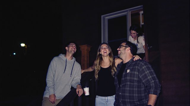 Disposable Camera example: three friends laughing on a wooden front porch at night, lit by harsh direct on-camera flash