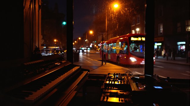 UK Garage example: an organ keyboard and turntables in a London flat at night, a night bus passing outside, sodium streetlight